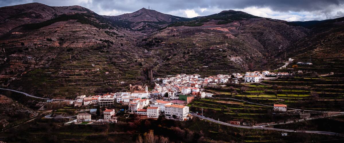 A mountainous landscape with terraced fields and a village with white buildings.