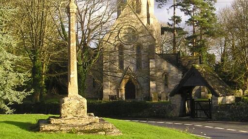 Leafield, Oxfordshire: village cross, with the spire and west end of St Michael and All Angels' parish church in the background. The base of the cross is probably 15th-century. The current shaft and top are a monument thanking God for Leafield's deliverance from an outbreak of smallpox in 1873.