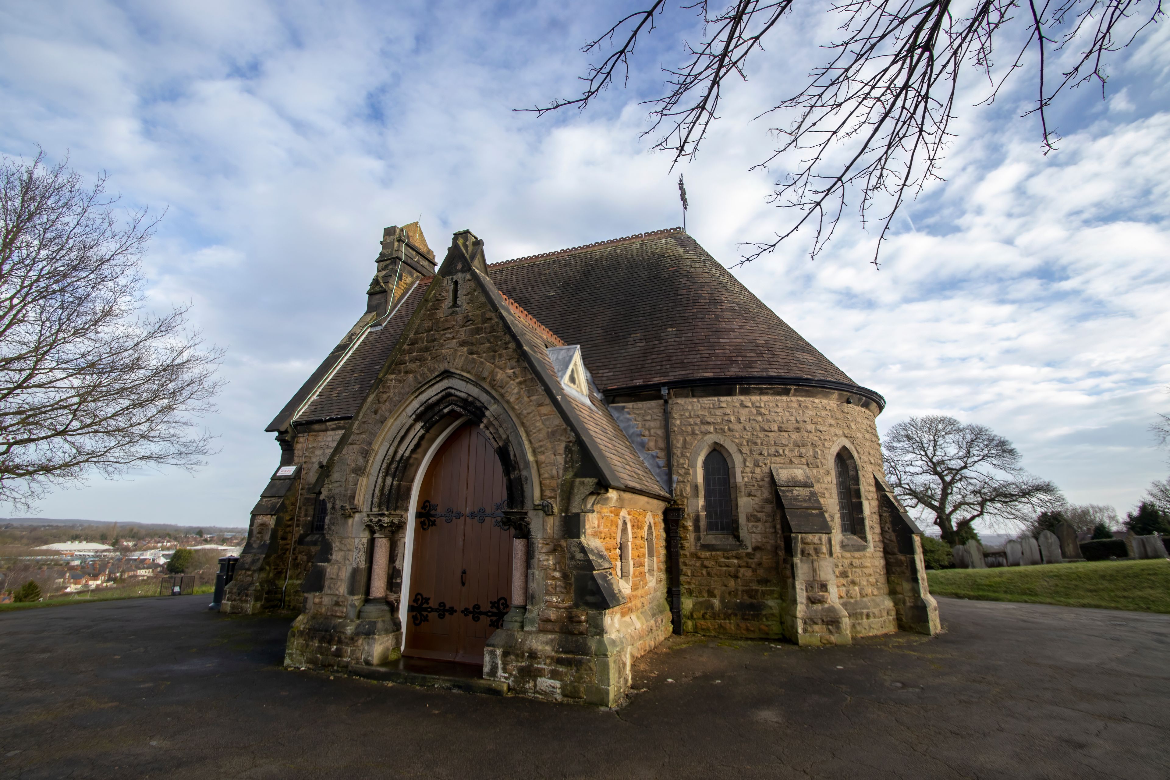 Une église historique en pierre, dotée d’un toit en flèche et de fenêtres en arc.