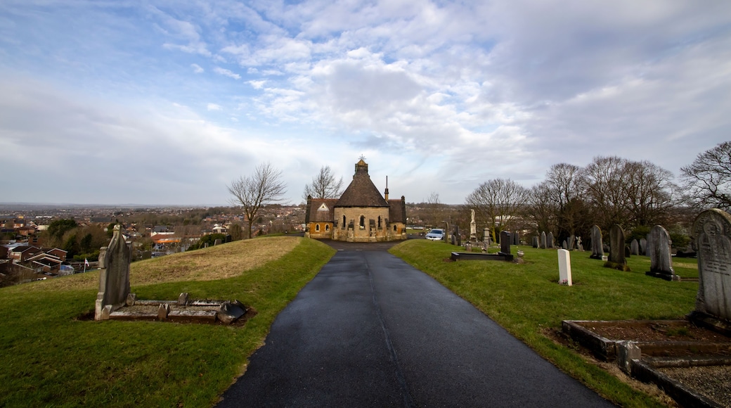 Une église avec un clocher, un cimetière et une route qui y mène.