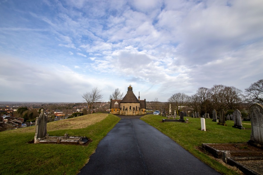 Una iglesia con campanario, un cementerio y una carretera que lleva a él.