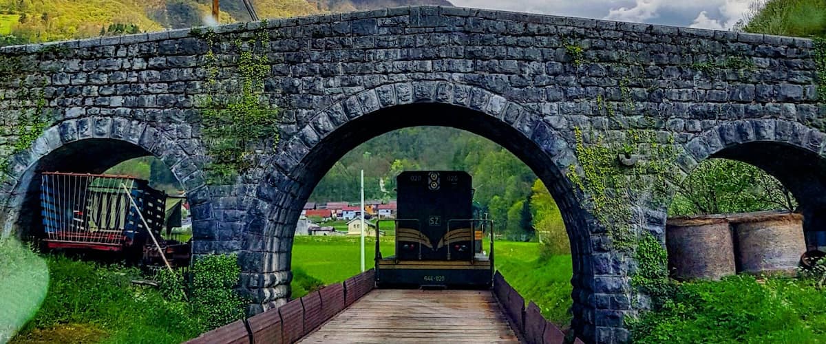 A stone bridge with two arches over a wooden pathway.