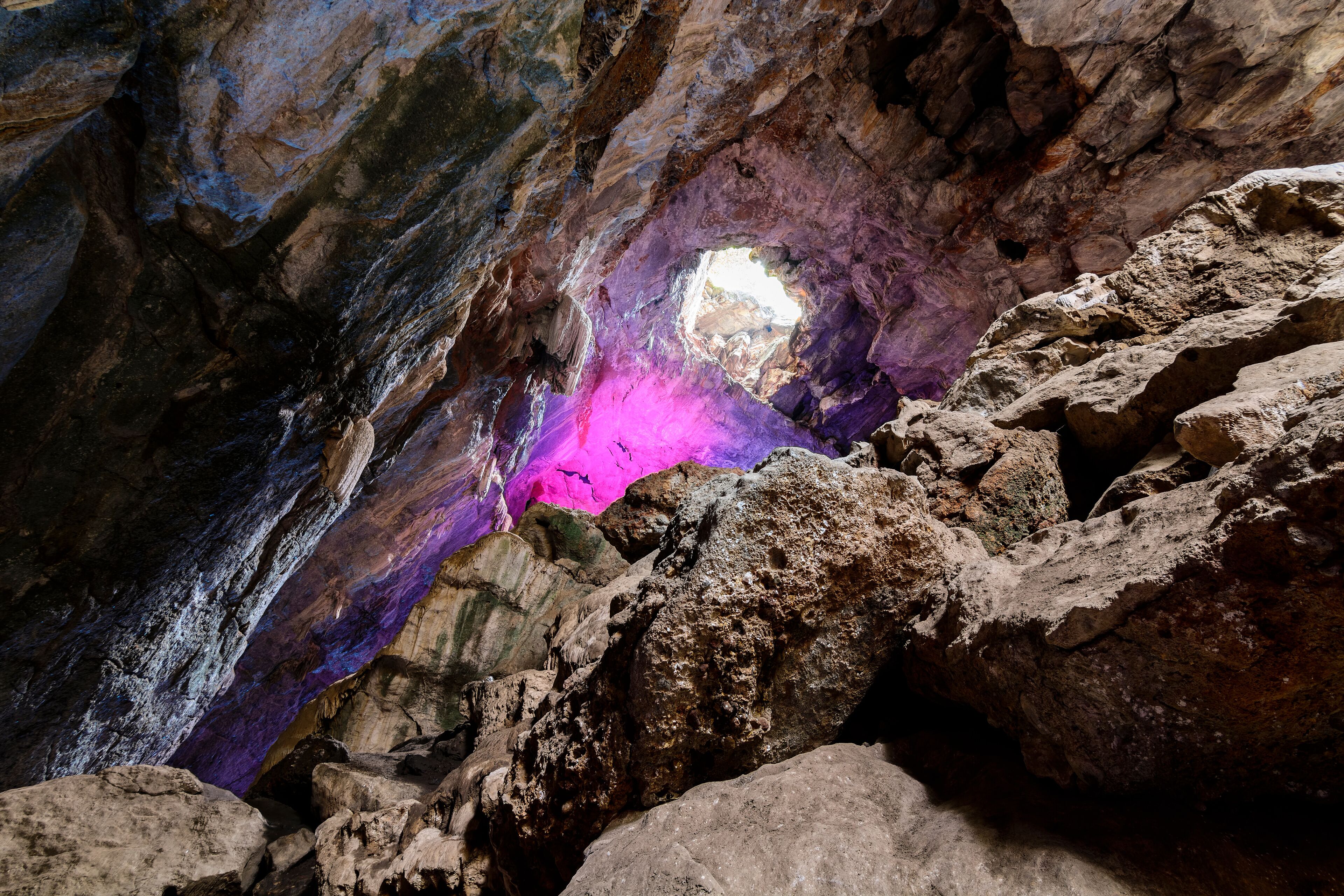 A cave with a purple glow and a natural rock formation.