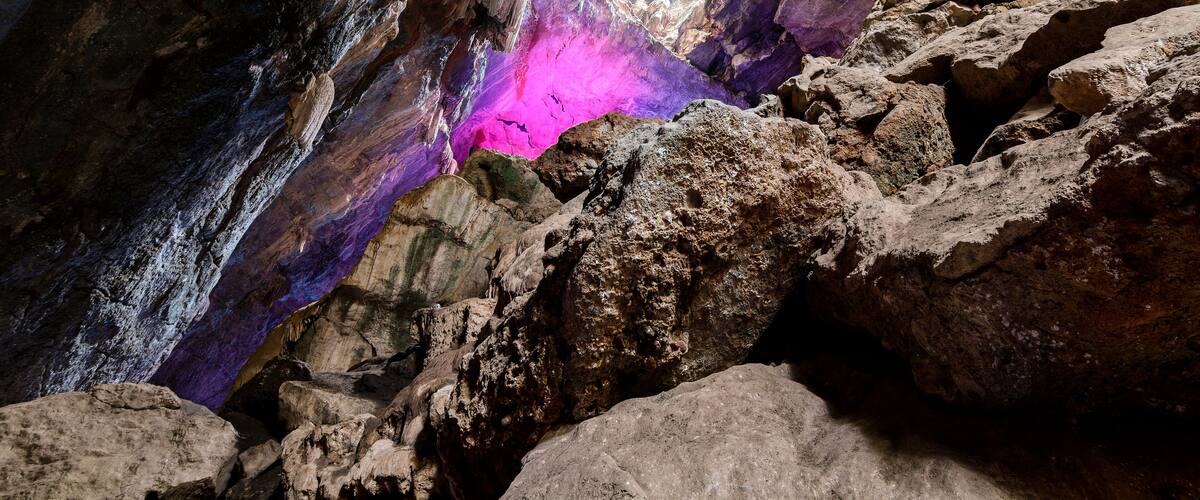 A cave with a purple glow and a natural rock formation.