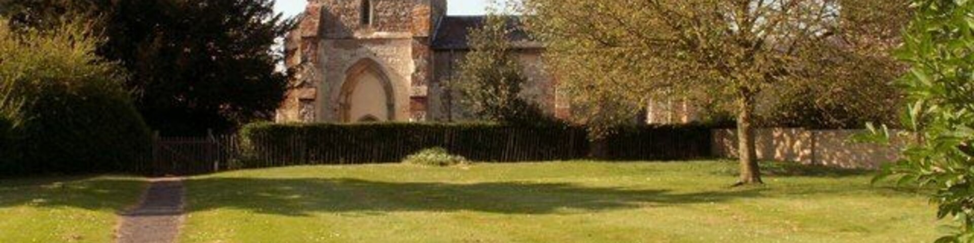Una iglesia con una torre, rodeada por un campo cubierto de césped y árboles.