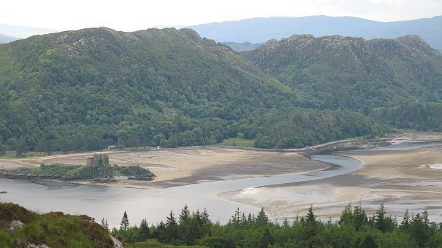 Castle Tioram and Cruach nam Meann Craggy hillsides above Loch Moidart and the outflow of the River Sheil. View from Eilean Shona.