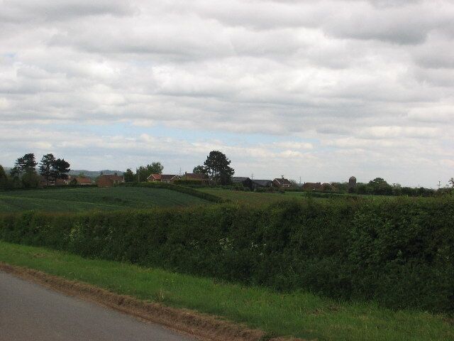 A rural landscape with a road, green fields, and scattered houses.