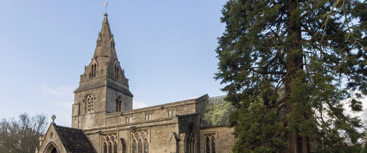 A historic church with a tall spire and Gothic architecture, surrounded by a cemetery with headstones.