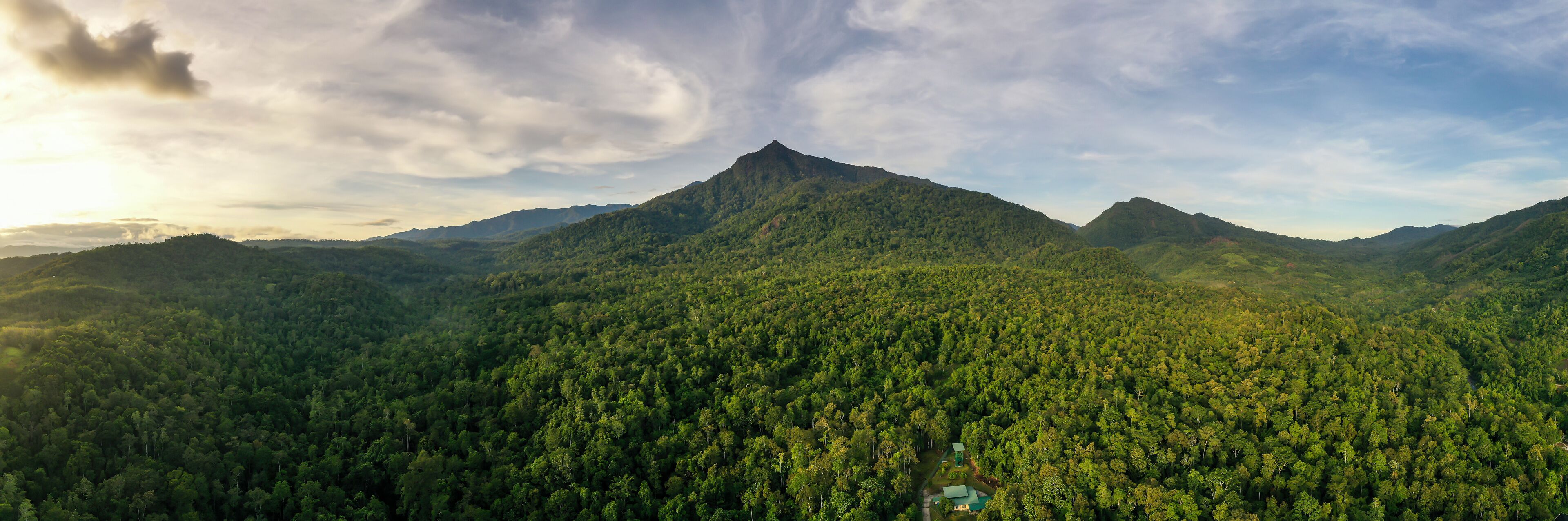 Scenic view of Mount Nambuyukon surrounded by lush tropical rainforest in Serinsim, Kota Marudu, Sabah, Malaysia. Beautiful mountain landscape with rich greenery under blue sky.