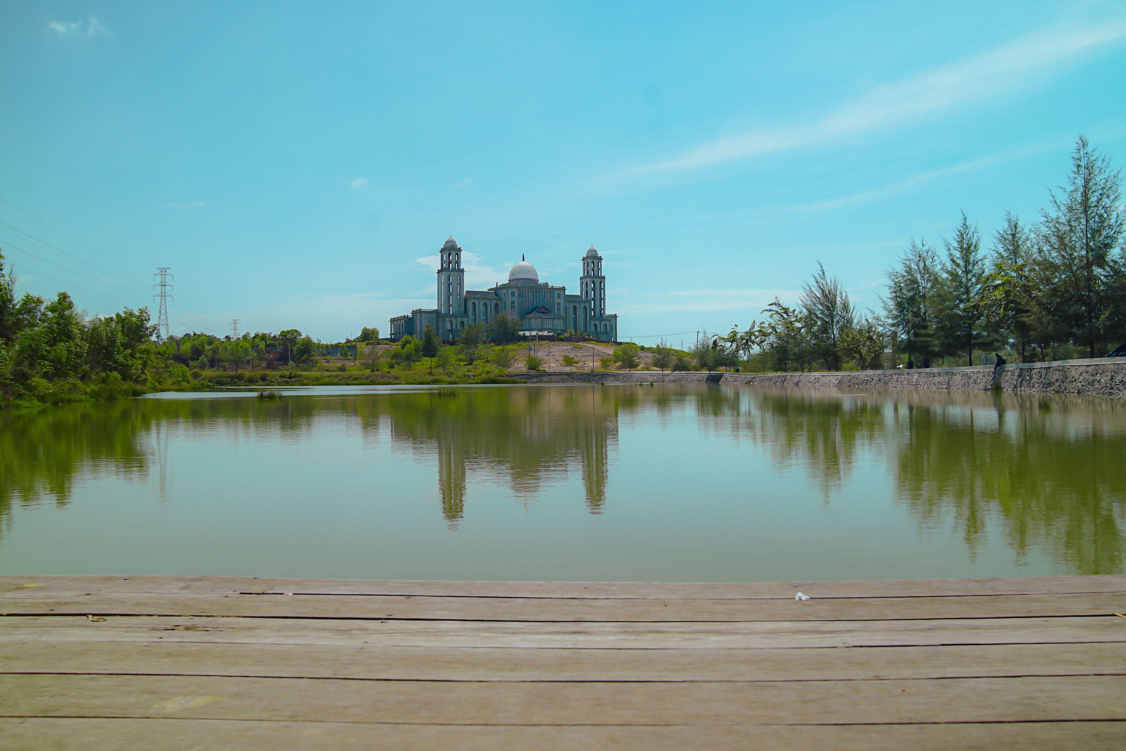 A large building with two towers and a dome, surrounded by a calm lake and greenery.