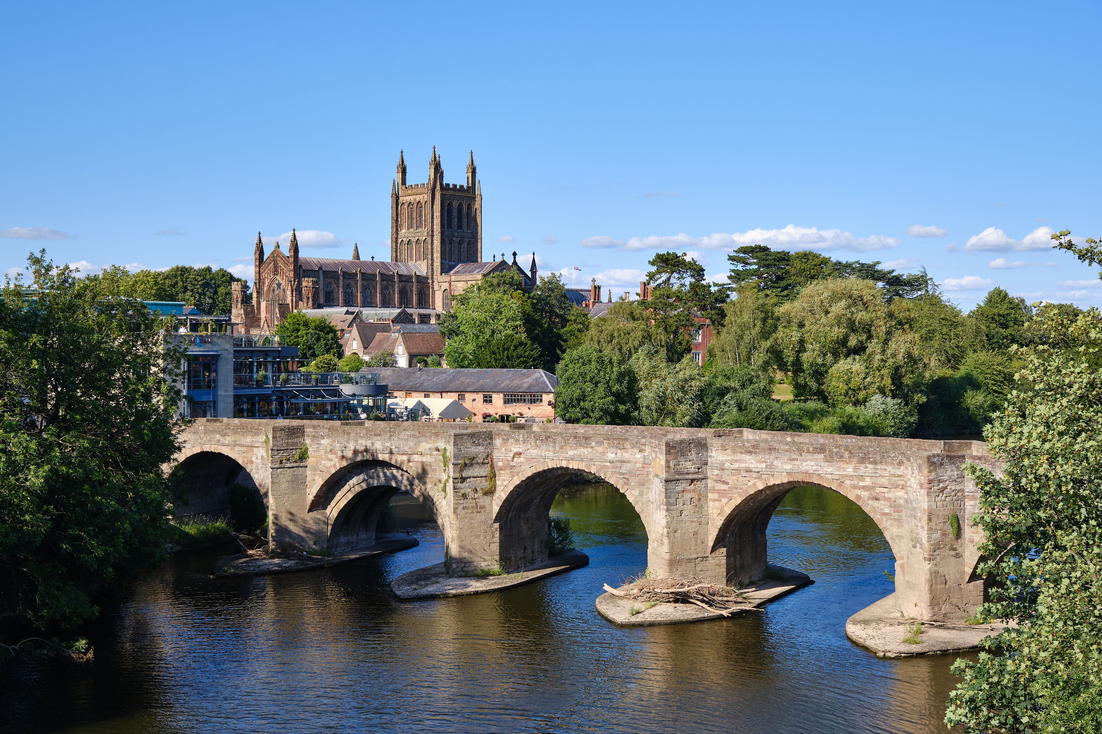 A stone bridge over a river with a historic church in the background.