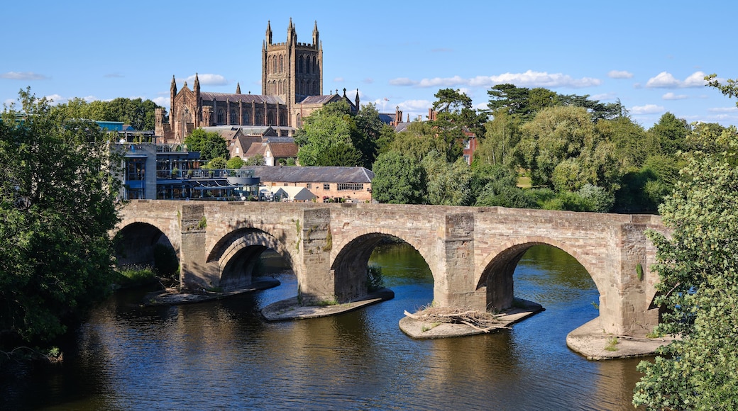 A stone bridge over a river with a historic church in the background.
