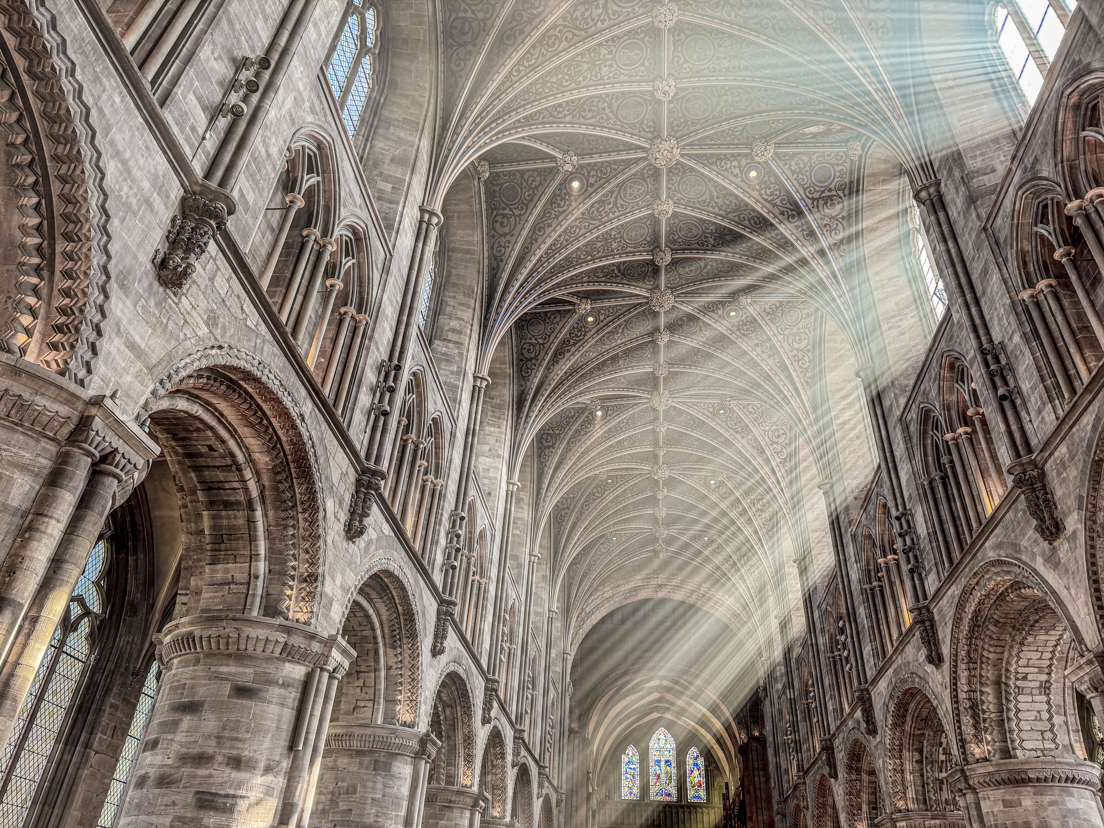 A cathedral interior with Gothic architecture, including pointed arches, ribbed vaults, and stained glass windows.