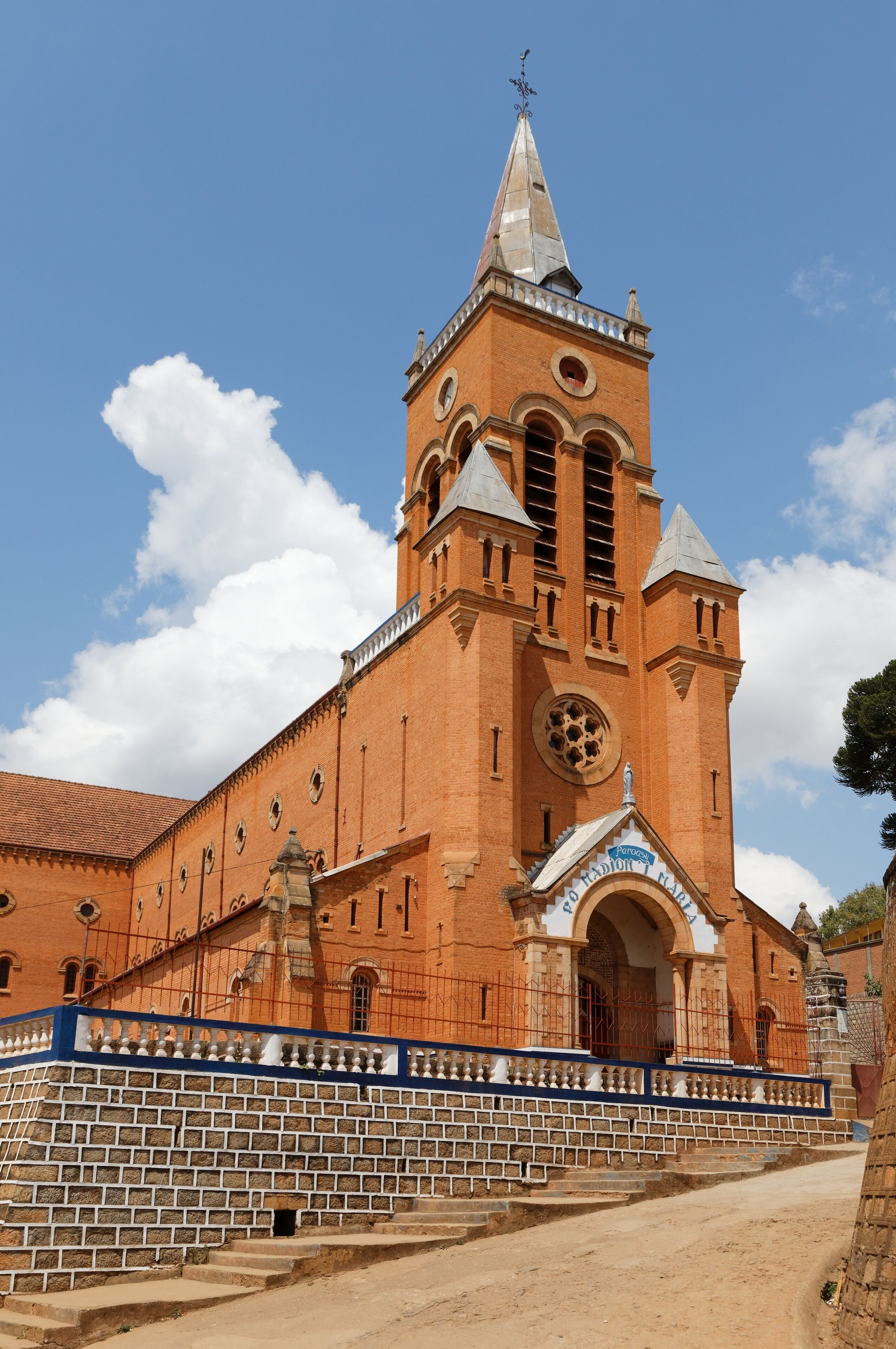 A large brick church with a tall bell tower and a blue entrance arch.