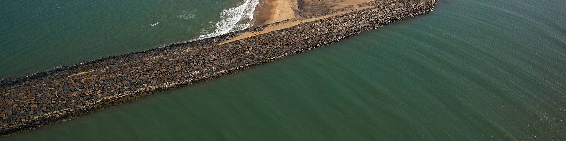 Aerial view of the tranquil coastline where the shimmering sea meets the sandy shore near Karaikal Beach, Karaikal, Puducherry, India.