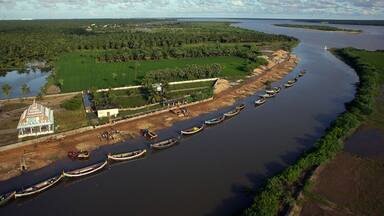 Yanam, India - 03 October 2010: Aerial view of the serene Godavari River winding past the vibrant green fields and boats docked along the shore near the temple.