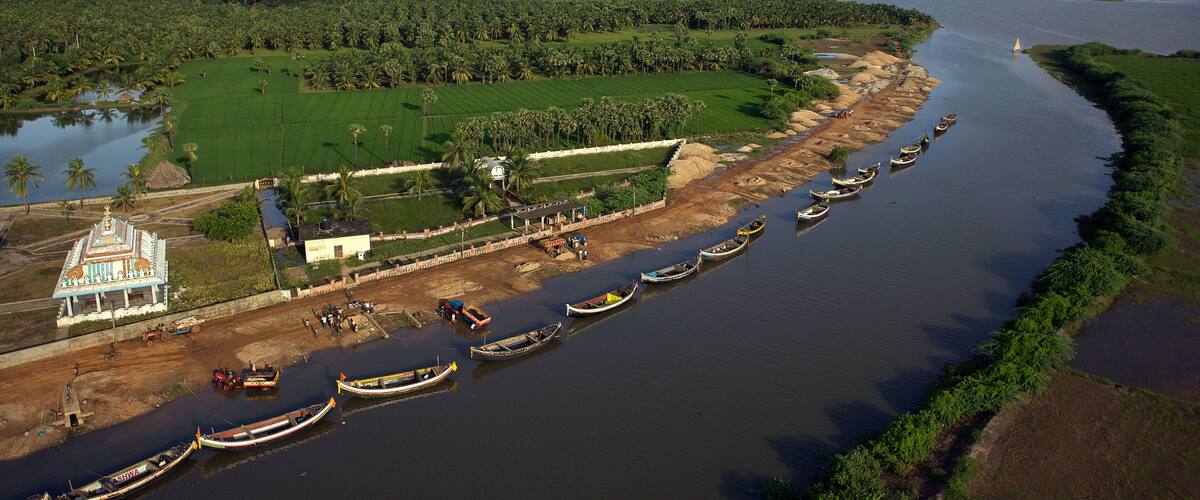 A river with boats, a temple, and surrounding greenery.