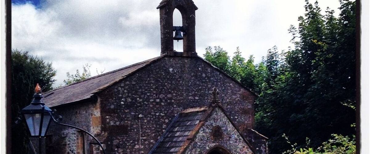 A historic church with a bell tower and a sign in front.