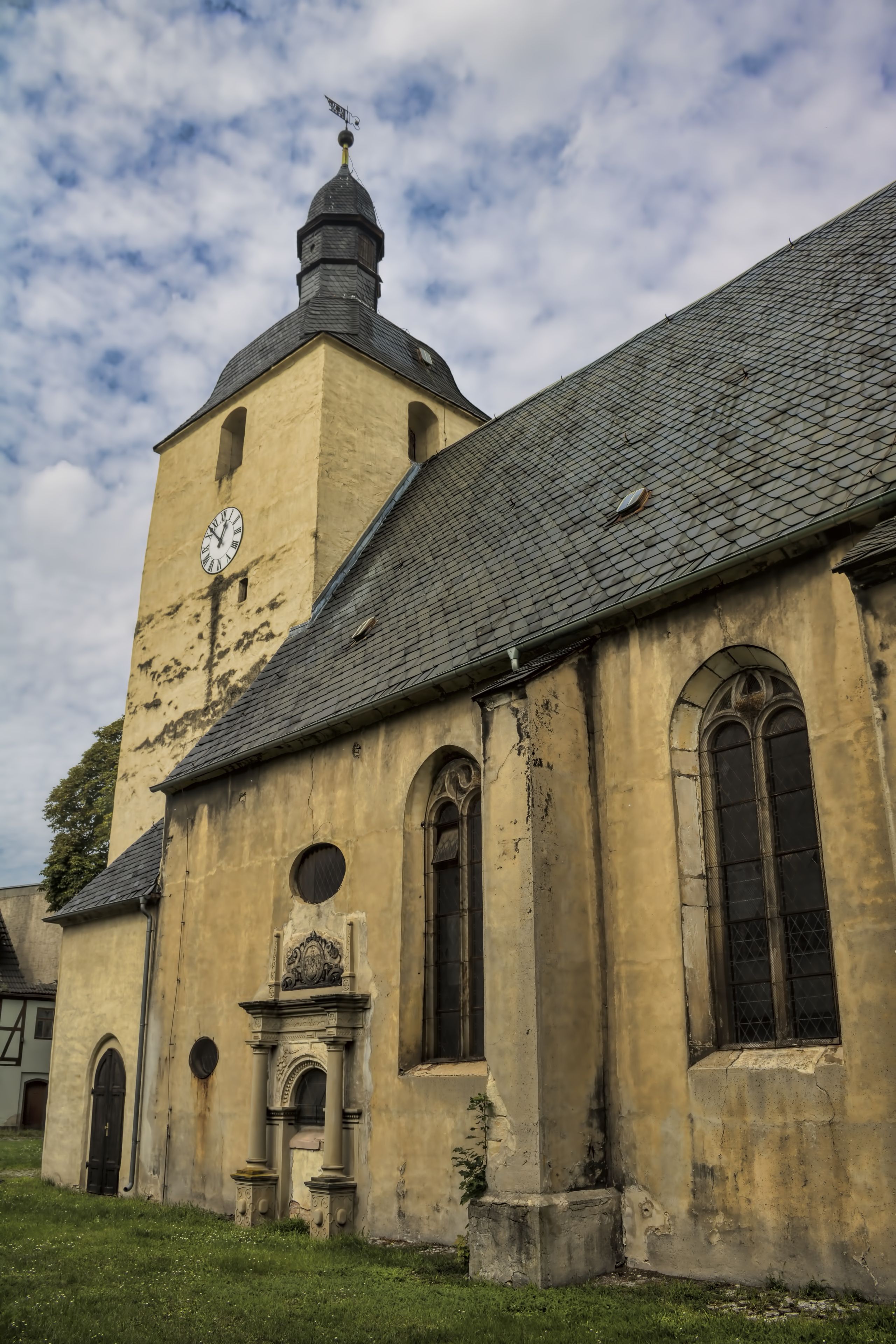 A historic church with a clock tower, arched windows, and a weather vane.