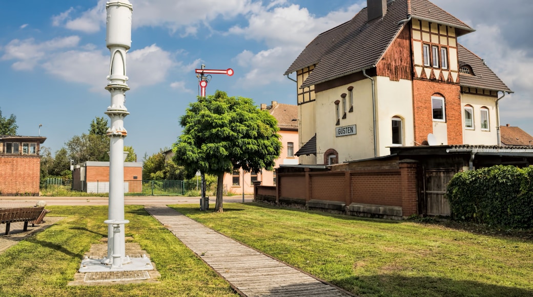 A traditional half-timbered house with a sign reading 'GÜSTEN' and a white signal post with a red arm.