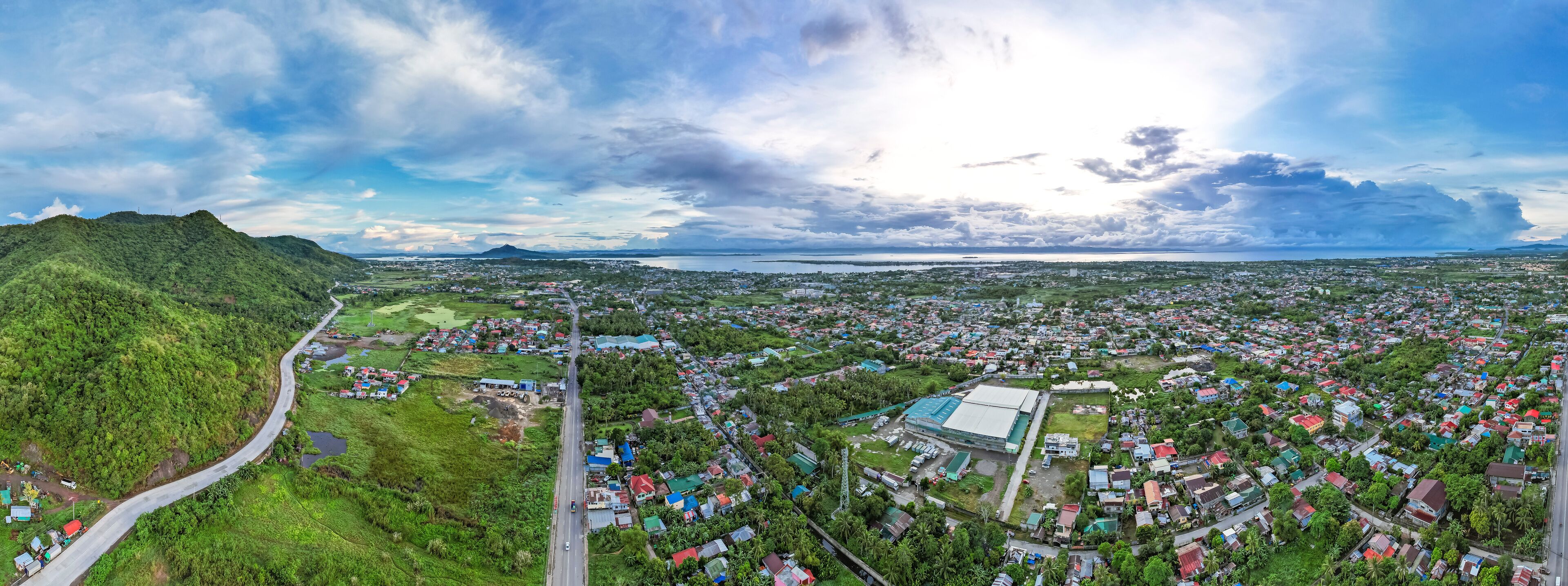 A coastal town with a winding road, dense housing, and a large body of water in the distance.