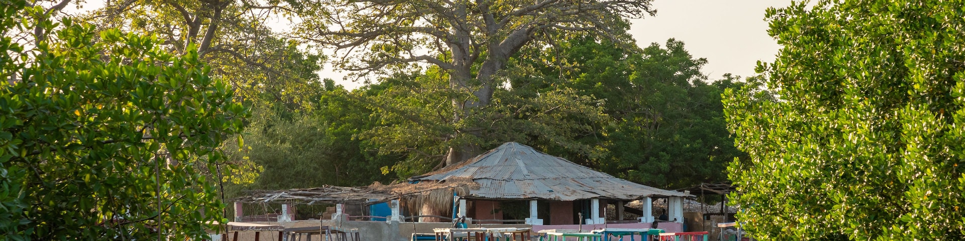 Escena a orillas del río con una casa y varias embarcaciones amarradas.