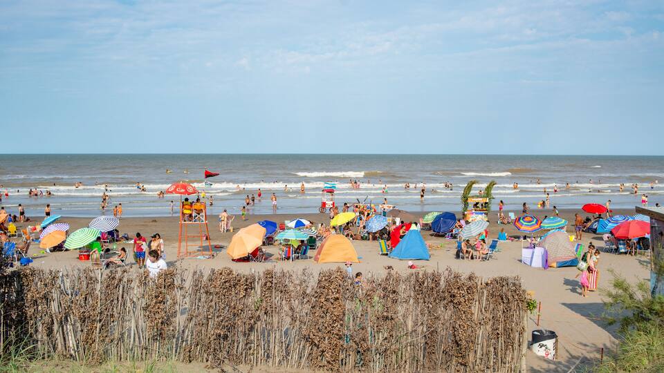 A crowded beach with people, tents, and colorful umbrellas.