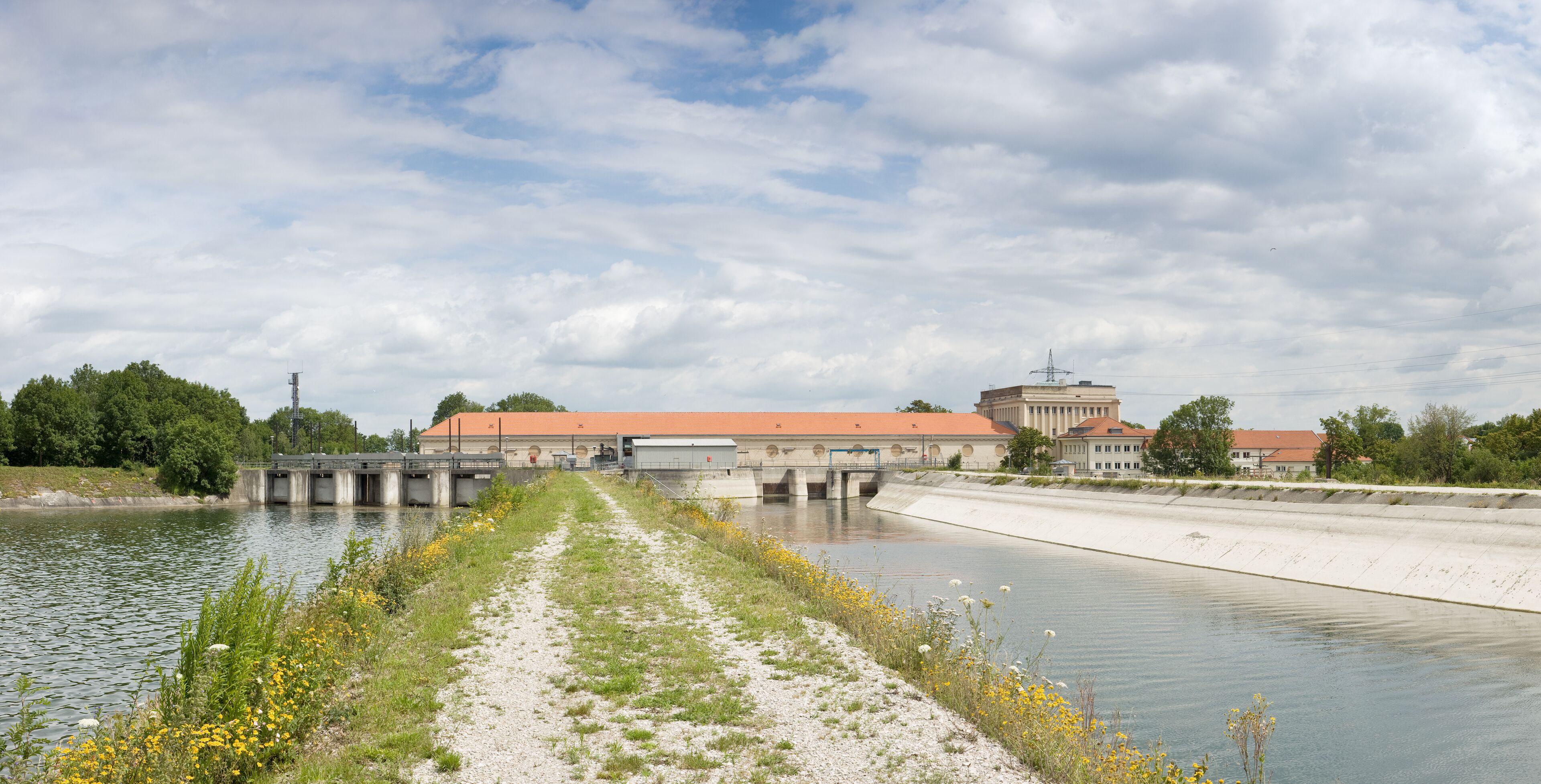 A canal with a bridge, buildings, and a cloudy sky.