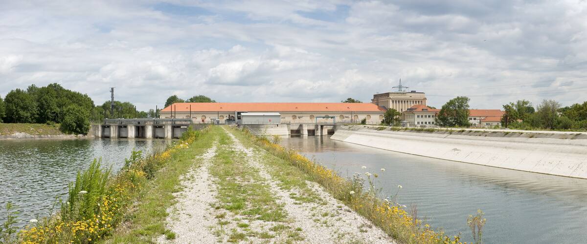 A canal with a bridge, buildings, and a cloudy sky.