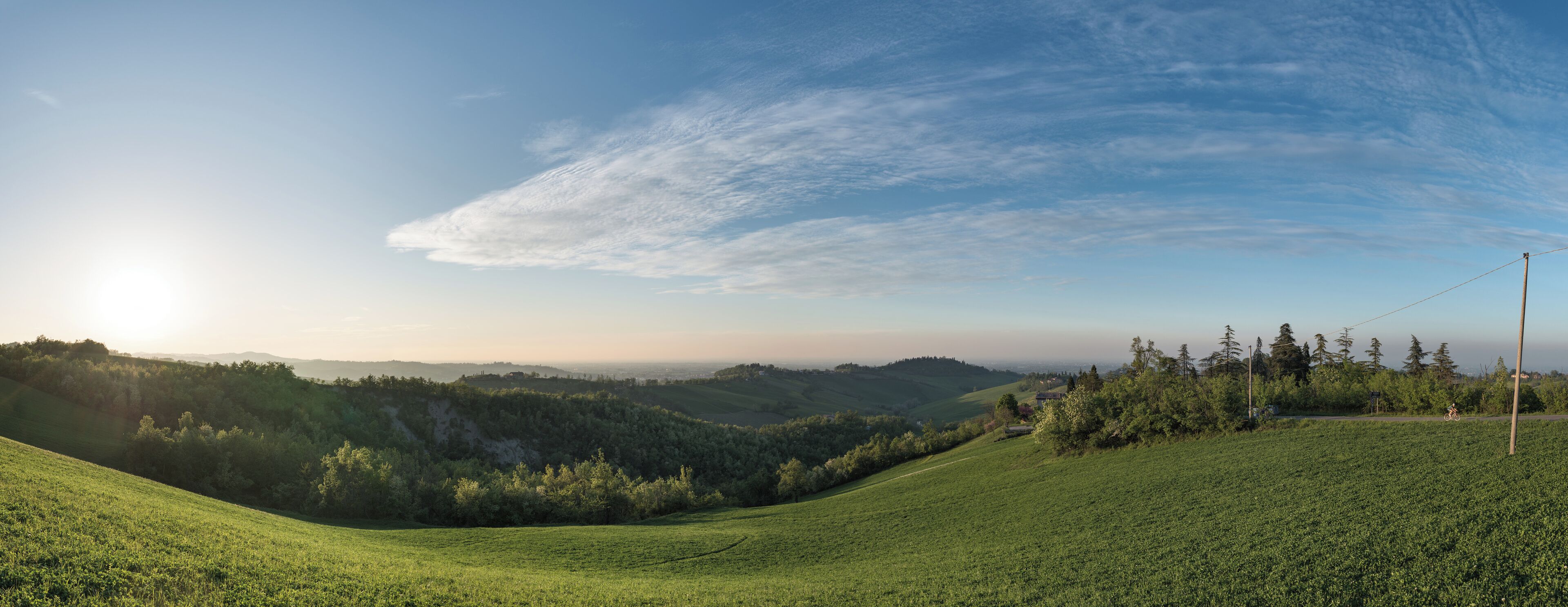 A green hillside with a clear sky and distant mountains.