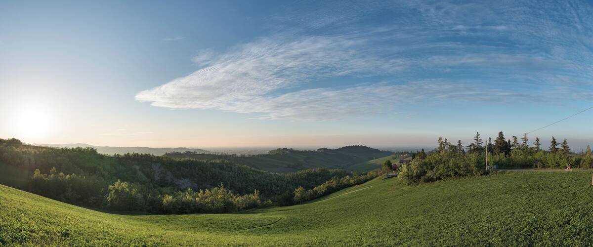 A green hillside with a clear sky and distant mountains.
