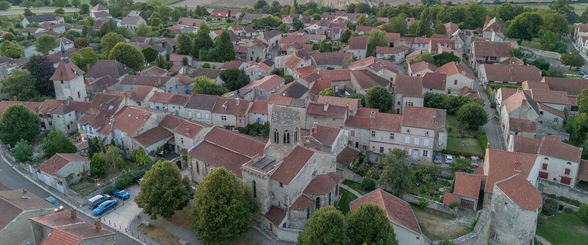 A historic village with red-tiled roofs, stone buildings, and a church with a bell tower.