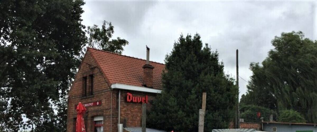 A small brick building with a red roof and a sign that reads "Duvel."