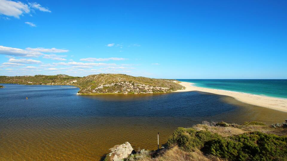 A coastal landscape with a sandy beach, clear blue waters, and a small island.