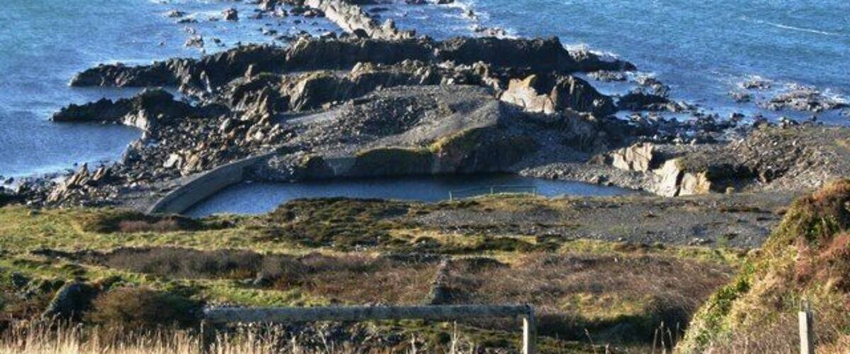 A rocky coastline with a clear view of the sea and distant land.
