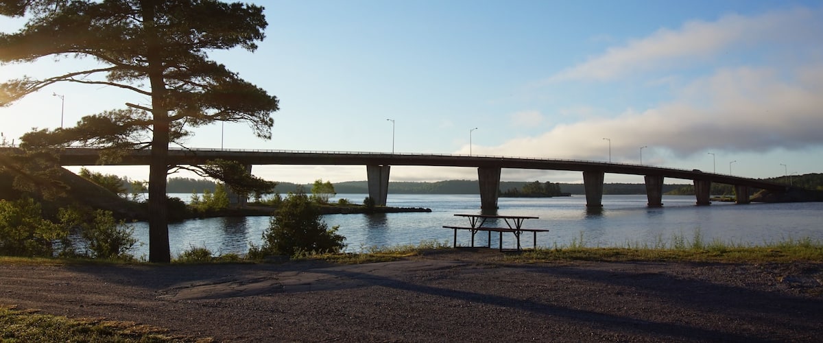 A bridge over a river with a picnic table in the foreground.