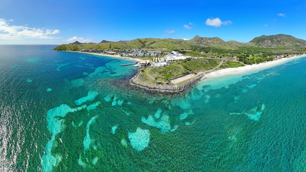 Une île tropicale aux eaux turquoise et limpides, bordée d’une plage de sable blanc et d’une végétation luxuriante.