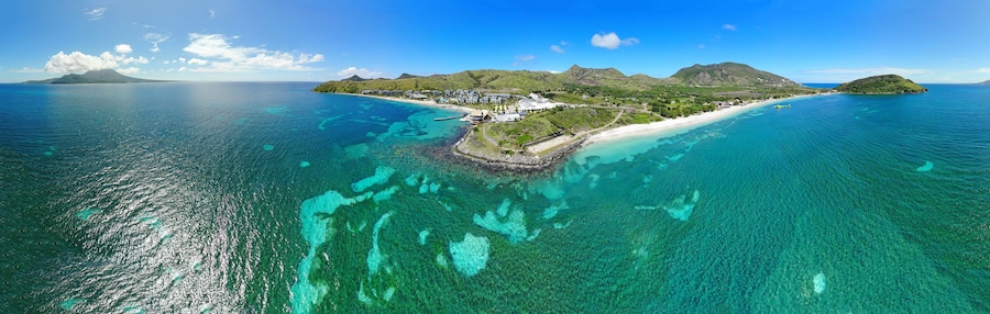 Una isla tropical con aguas turquesas cristalinas, una playa de arena blanca y exuberante vegetación.