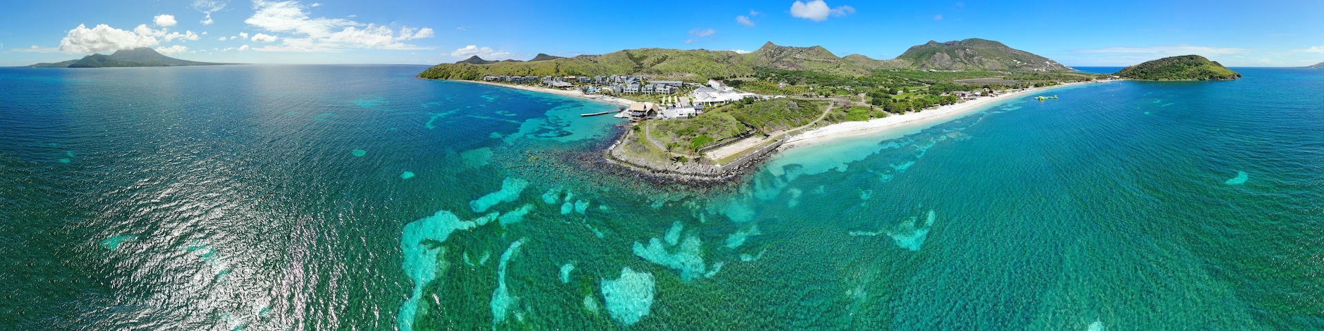 Una isla tropical con aguas turquesas cristalinas, una playa de arena blanca y exuberante vegetación.