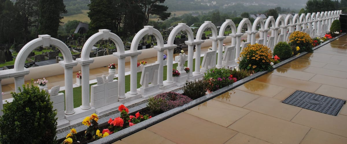 A cemetery with white arches and flower beds.
