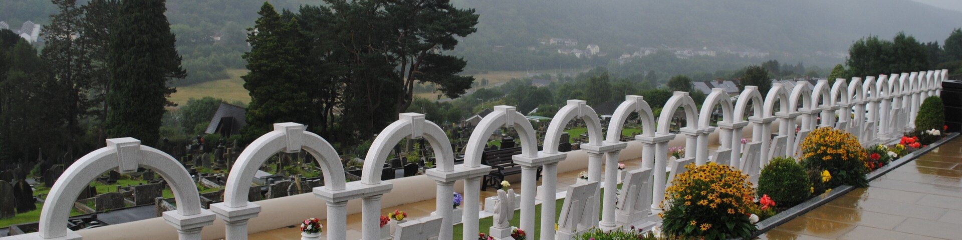 A cemetery with white arches and flower beds.