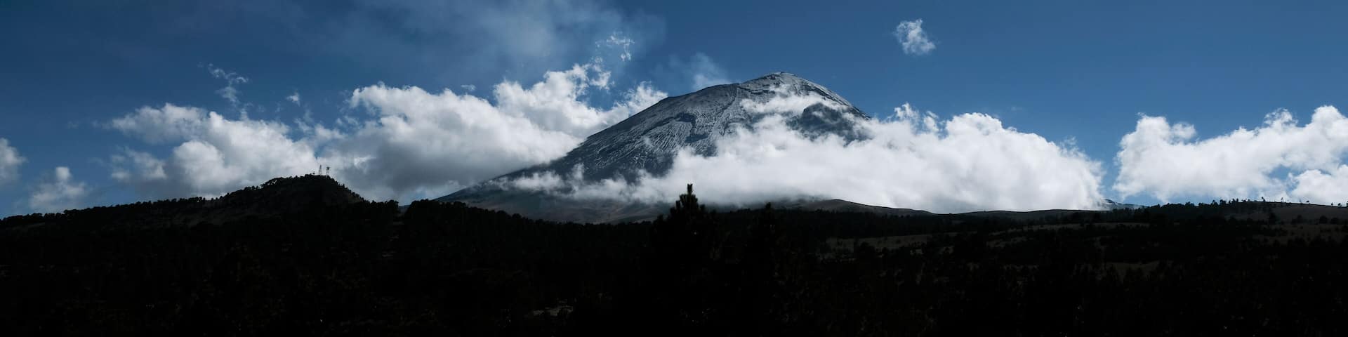 Popocatepetl mexican volcano surrounded by clouds in a cold and sunny day of winter