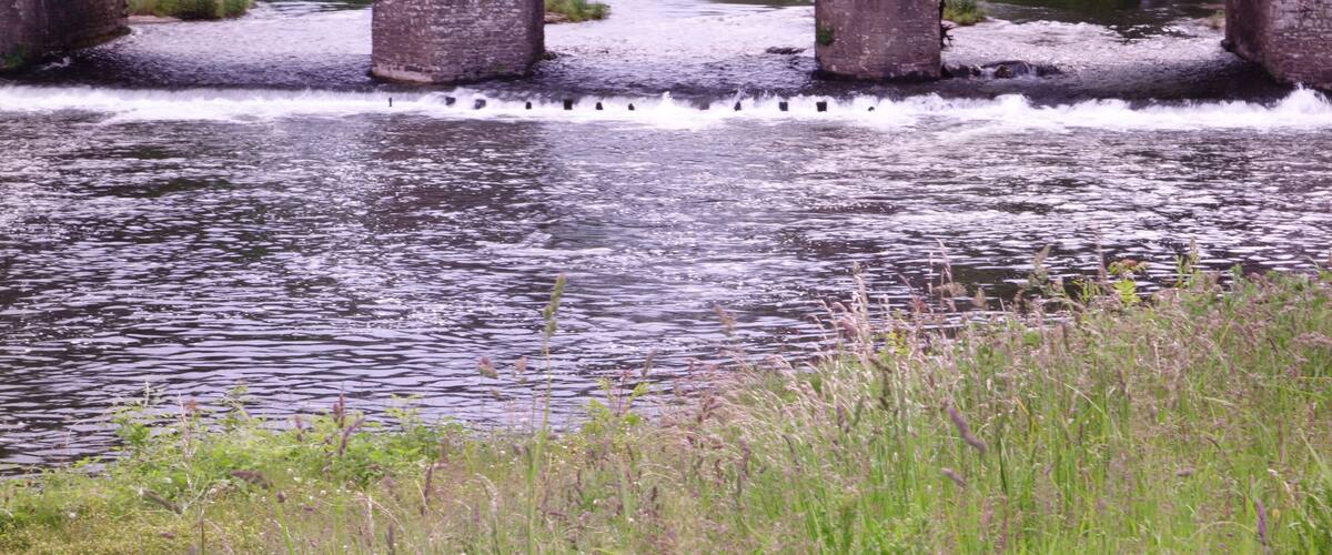 A stone bridge over a river with water flowing beneath it.