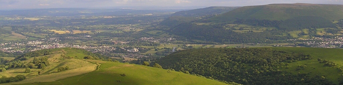 A panoramic view of rolling hills, a town, and a river.