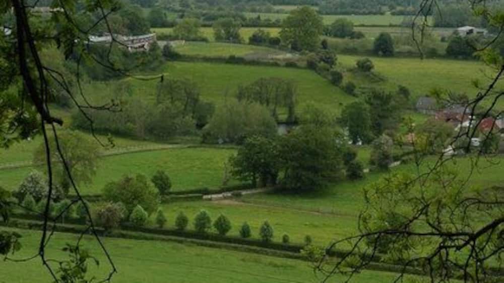 Ein üppiges, grünes Tal mit sanften Hügeln, einem fernen Berg und einer kleinen Stadt im Hintergrund.