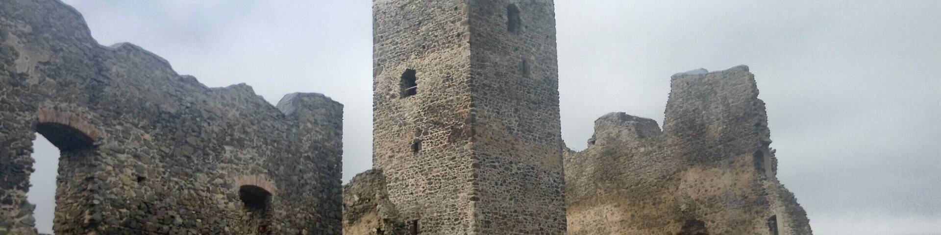 A stone tower with a flag atop, surrounded by ruins.