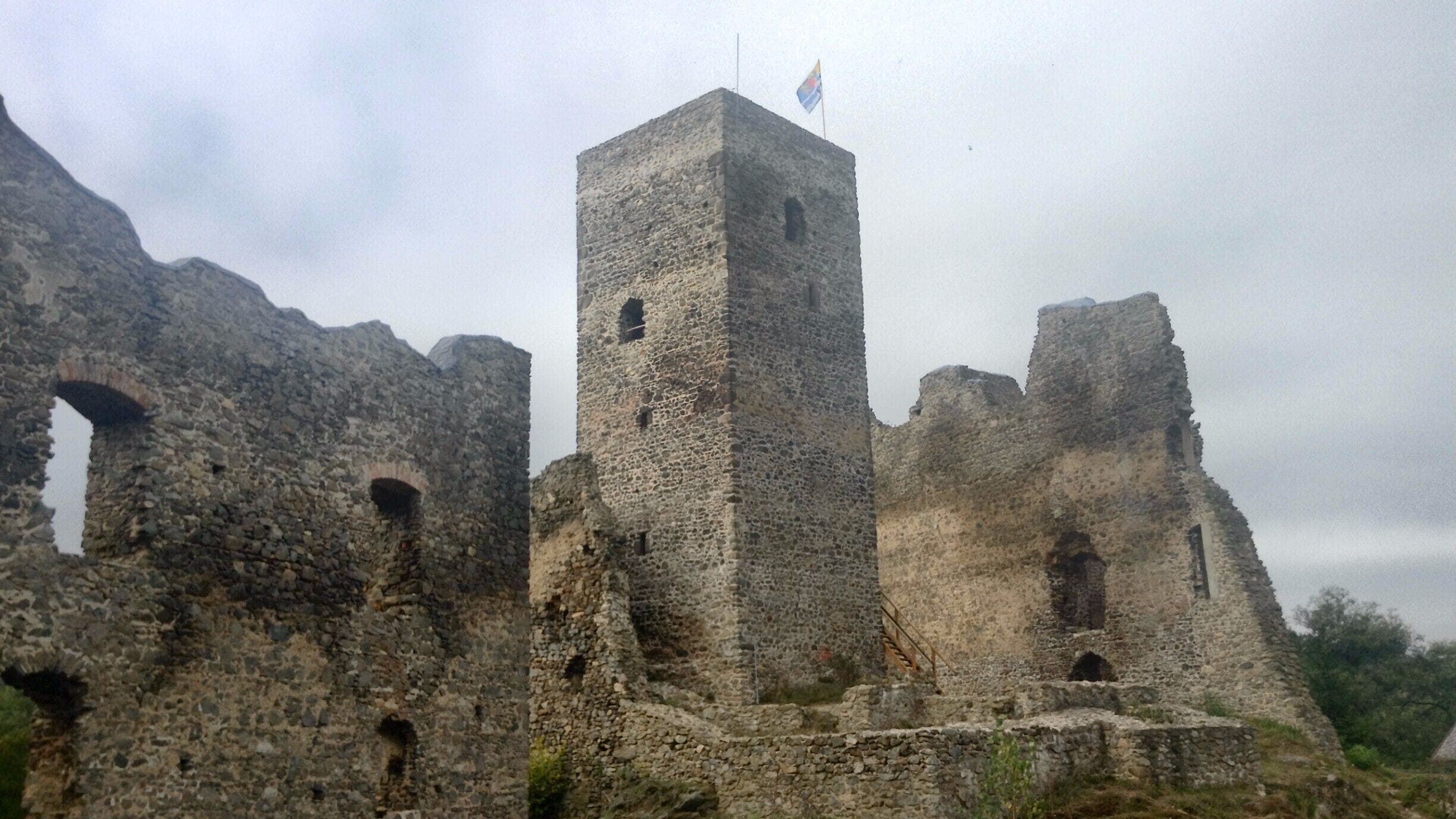 A stone tower with a flag atop, surrounded by ruins.