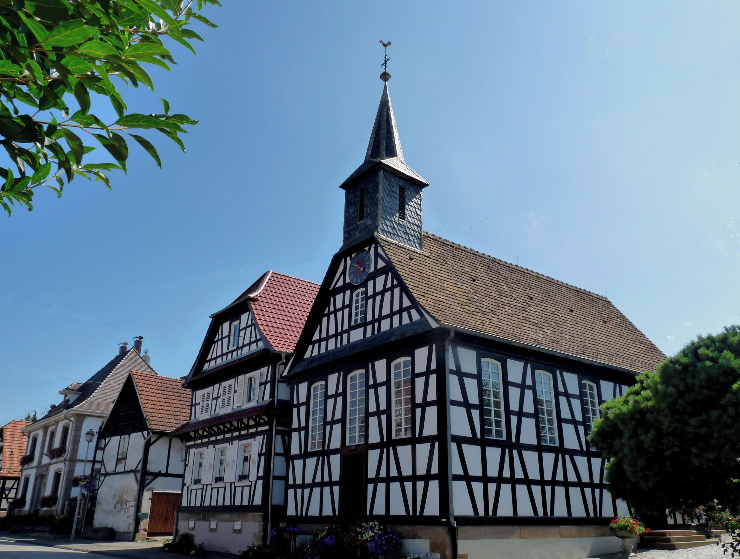 A traditional half-timbered building with a clock tower and a red-tiled roof.