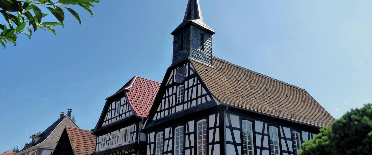 A traditional half-timbered building with a clock tower and a red-tiled roof.