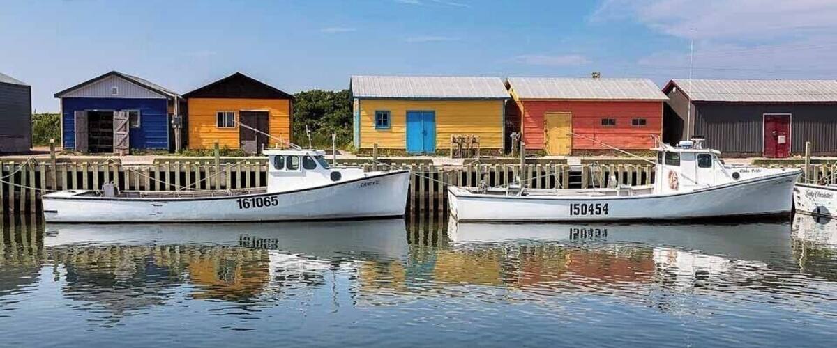 Two boats docked at a pier with colorful buildings in the background.